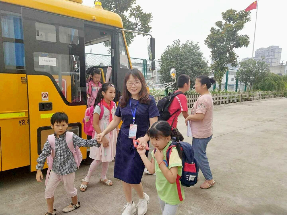 圖為校車照管員阿姨護(hù)送孩子上下學(xué)。