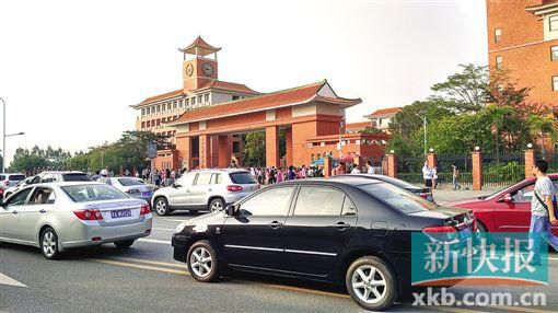 學(xué)校門口的路段停滿前來(lái)接送孩子的車輛,不少家長(zhǎng)在校門口等候。