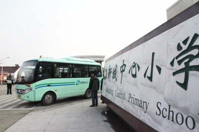鎮村公交校車按順序駛出校園送學生回家。